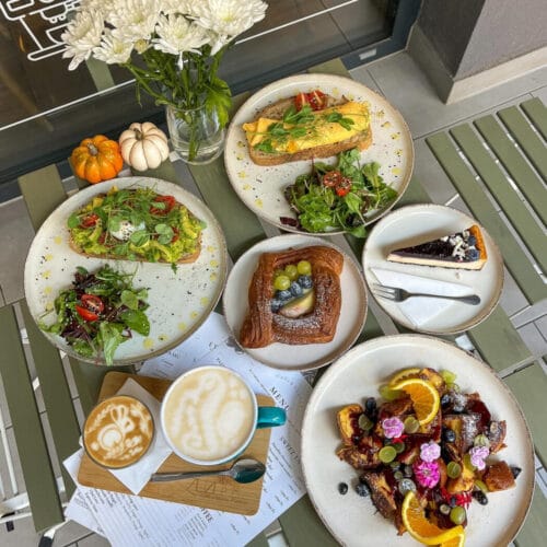 Reggeliző asztal avokádós pirítóssal, péksüteménnyel, gyümölcsös desszerttel és latte-val a Zuzu cafe&bakeryben